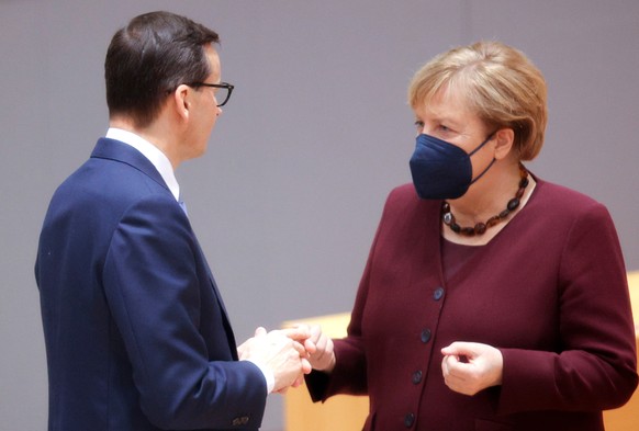 epa09538492 Poland?s Prime Minister Mateusz Morawiecki (L), speaks with German Chancellor Angela Merkel during a round table meeting at an EU summit in Brussels, Belgium, 22 October 2021. European Uni ...