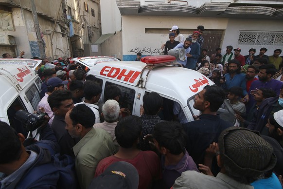 epa12756286 Rescue workers and people gather at the site of a residential compound following a suspected gas leakage blast in Karachi, Pakistan, 19 February 2026. At least 16 people, including women a ...