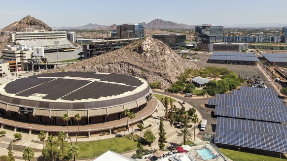 epa09329685 An aerial photo made with a drone shows solar panels placed above parking spaces and the roof of Desert Financial Arena on the campus of Arizona State University in Tempe, Arizona, USA, 07 ...