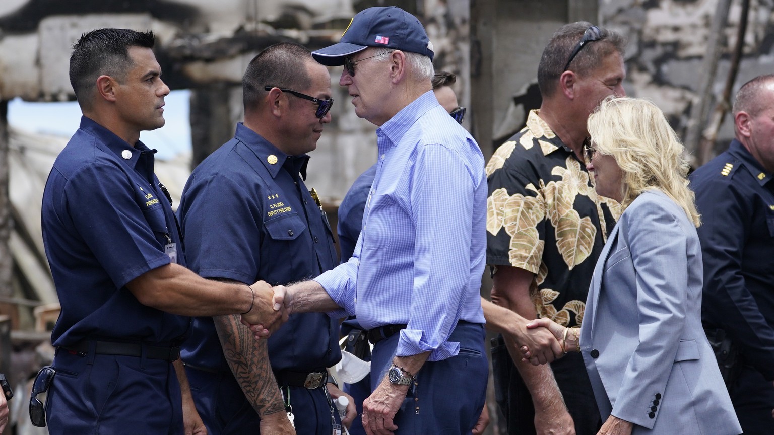 President Joe Biden and first lady Jill Biden greet first responders as they tour areas devastated by the Maui wildfires, Monday, Aug. 21, 2023, in Lahaina, Hawaii. In the background is the massive Ba ...