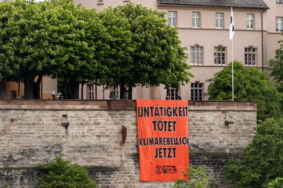 Ein Transparent, das zur Klimarebellion aufruft, haengt an der Mauer der Pfalz in Basel, am Freitag, 21. Mai 2021. (KEYSTONE/Georgios Kefalas)