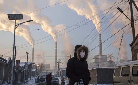 SHANXI, CHINA -NOVEMBER 26: (CHINA, HONG KONG, MACAU, TAIWAN OUT) Smoke billows from stacks as a Chinese woman wears as mask while walking in a neighborhood next to a coal fired power plant on Novembe ...