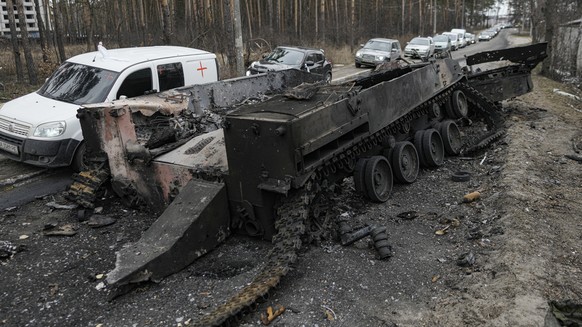 FILE - Cars drive past a destroyed Russian tank as a convoy of vehicles evacuating civilians leaves Irpin, on the outskirts of Kyiv, Ukraine, March 9, 2022. (AP Photo/Vadim Ghirda, File)