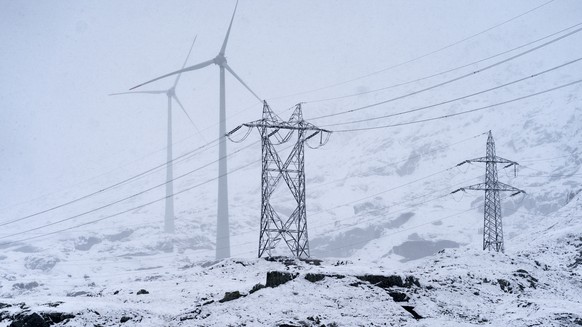 Eine Hochspannungsleitung und zwei der fuenf Windkraftanlagen mit einem 98 Meter hohen Mast und einem Rotor mit einer Spannweite von 92 Metern, die sich auf dem Gotthardpass befinden, aufgenommen in e ...