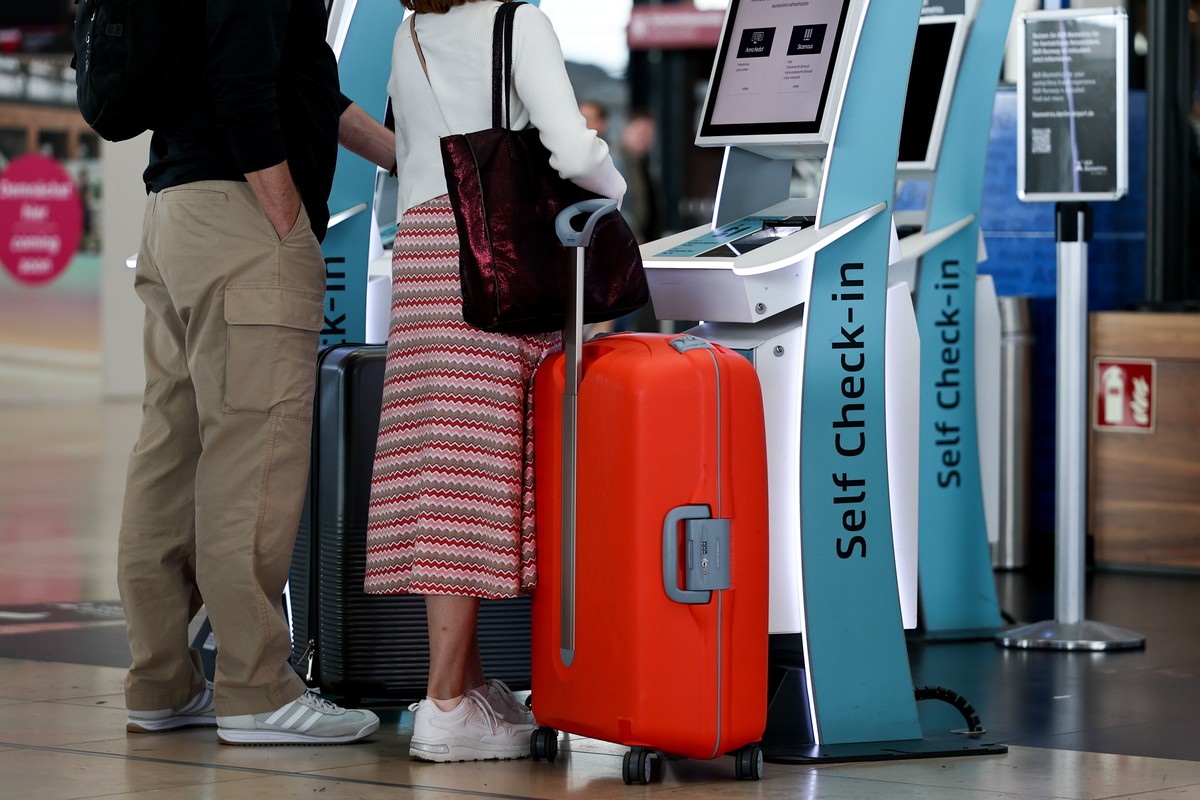 epa12242944 Passengers stand next to a self check-in terminal at the Berlin Brandenburg Airport in Schoenefeld, Germany, 17 July 2025. Berlin Airport is preparing for a surge of passengers at the star ...