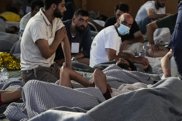 Survivors of a shipwreck rest in a warehouse at the port in Kalamata town, about 240 kilometers (150 miles) southwest of Athens, Wednesday, June 14, 2023. A fishing boat carrying migrants trying to re ...