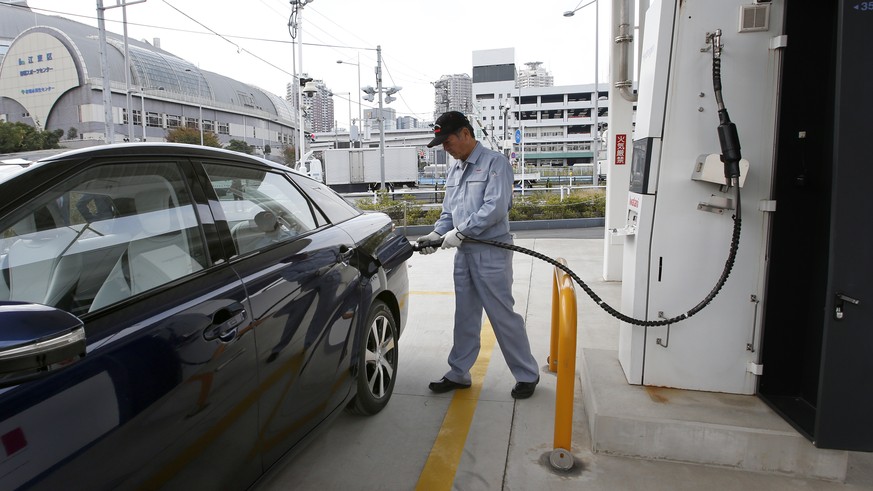 In this photo taken Monday, Nov. 17, 2014, a fuel cell charge station worker demonstrates how to charge hydrogen to a Toyota Motor Corp.&#039;s new fuel cell vehicle Mirai at a charge station near Toy ...