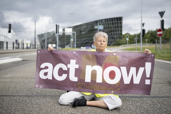 Klimaaktivisten von Act Now! blockieren die Hauptstrasse am Flughafen, aufgenommen am Mittwoch, 24. Juli 2024 in Zuerich. (KEYSTONE/Ennio Leanza)