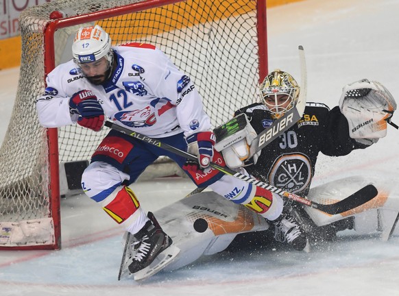 Zurich&#039;s player Pascal Pelletier, left, fights for the puck with LuganoÃs goalkeeper Elvis Merzlikins, right, during the first match of the playoff final of National League between HC Lugano and ...