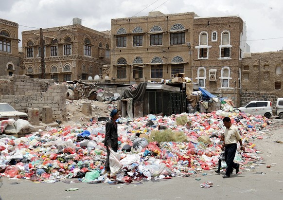 epa05946997 Yemenis walk past rubbish piled on a street after collections were halted due to a full strike in Sanaa, Yemen, 06 May 2017.According to reports, garbage collectors started a full strike i ...