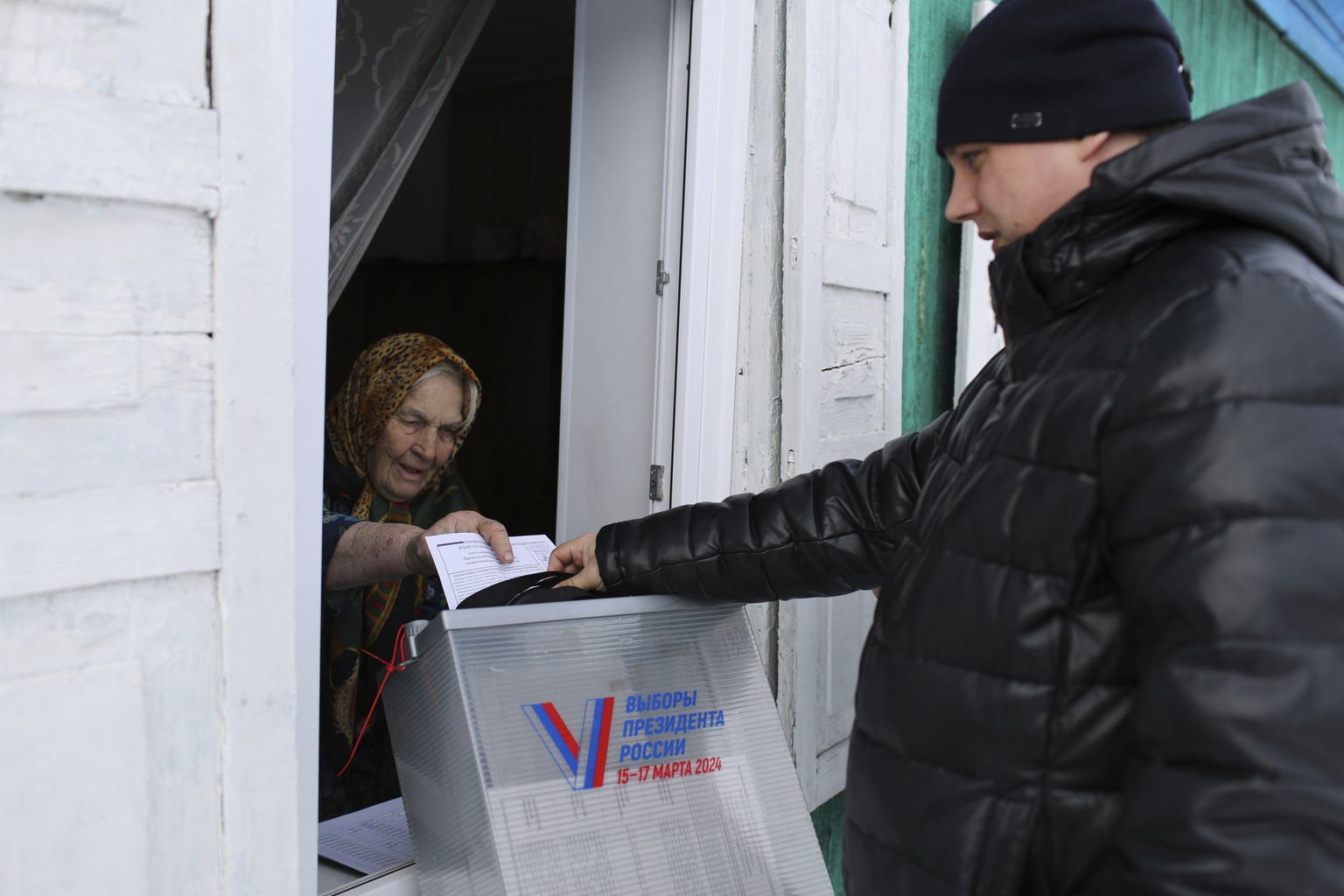 An elderly woman casts a ballot during a presidential election via a mobile election committee, who visit people who cannot physically attend a polling station, in Nikolayevka village outside Siberian ...