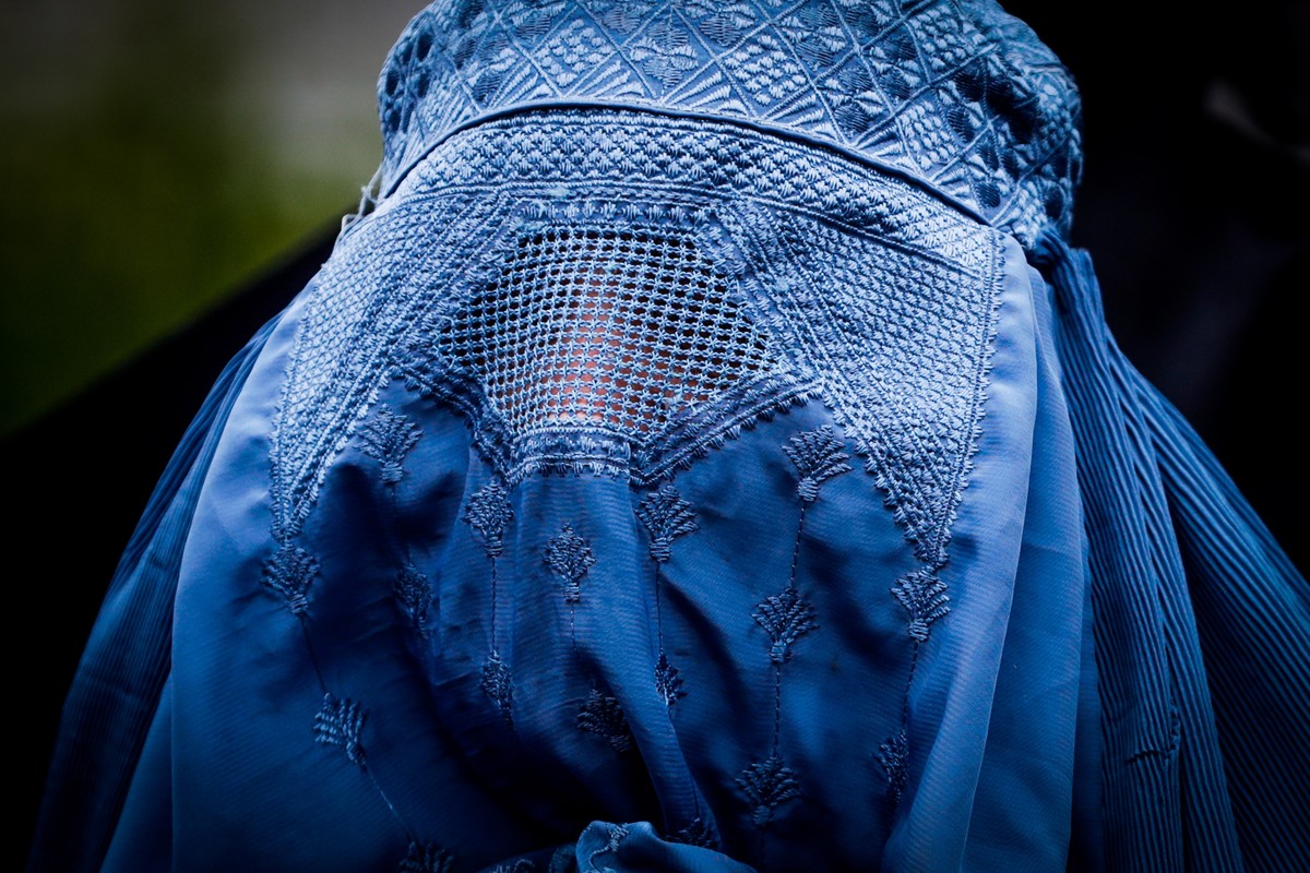 epa09419166 A women wears a burqua while people gather in front of the European Institutions in support of Afghans victims of the war, in Brussels, Belgium, 18 August 2021. The main purpose of the ral ...