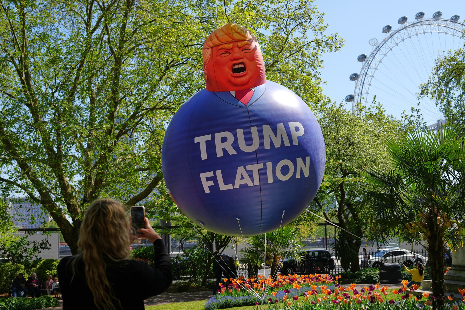A passer-by takes a picture of a balloon in the caricature of US President Donald Trump as Britain's Liberal Democrat party launch their new "Trumpflation" campaign as latest inflation  ...