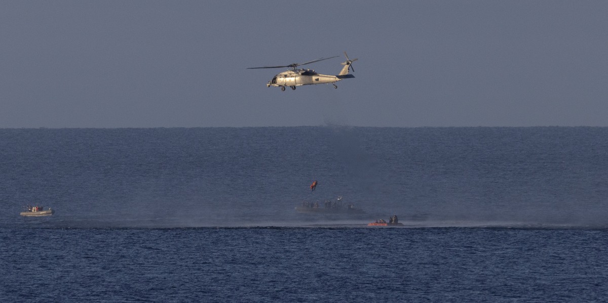 epa12882026 A handout photo made available by the National Aeronautics and Space Administration (NASA) shows a Navy MH-60 Seahawk as it lifts NASA astronaut Artemis II mission specialist Christina Koc ...