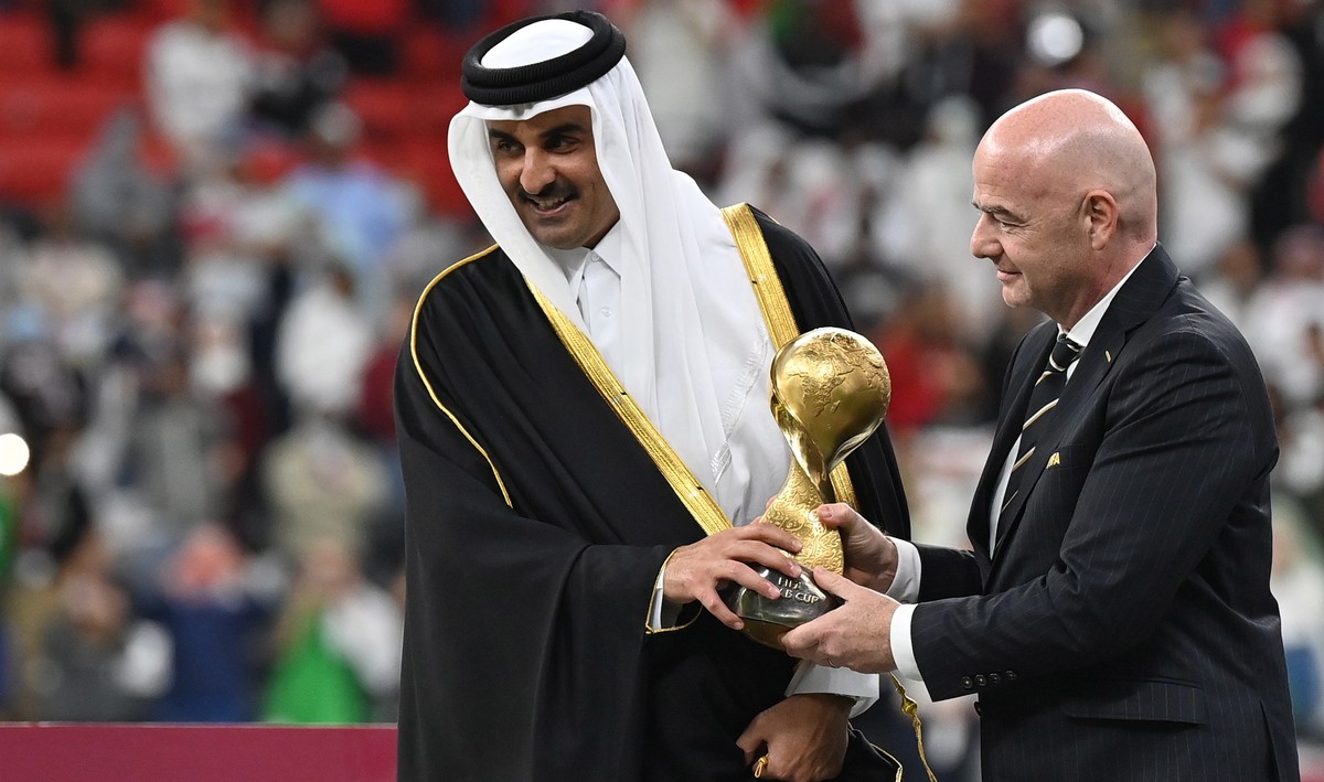 epa09648904 FIFA President Gianni Infantino (R) and Qatar's Emir Sheikh Tamim bin Hamad al-Thani (L) present the trophy after Algeria won the FIFA Arab Cup final match between Tunisia and Algeria ...