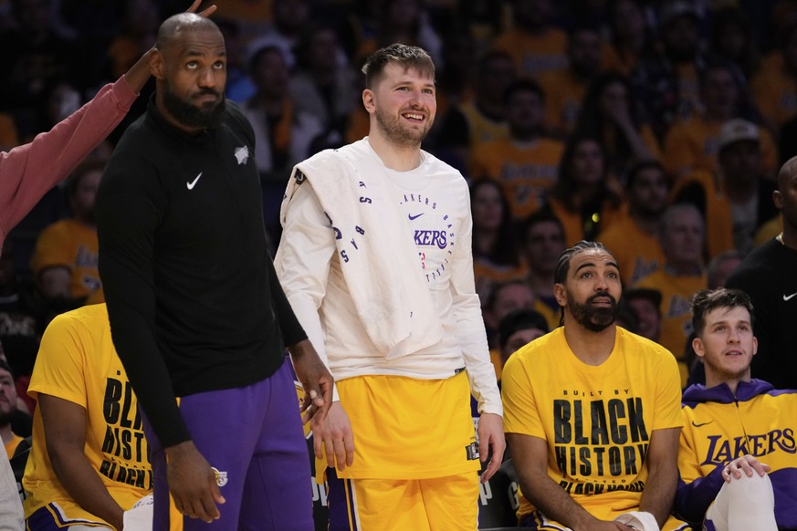 Los Angeles Lakers guard Luka Doncic, center, and teammate forward LeBron James, left, look on from the bench during the second half of an NBA basketball game against the Utah Jazz, Monday, Feb. 10, 2 ...