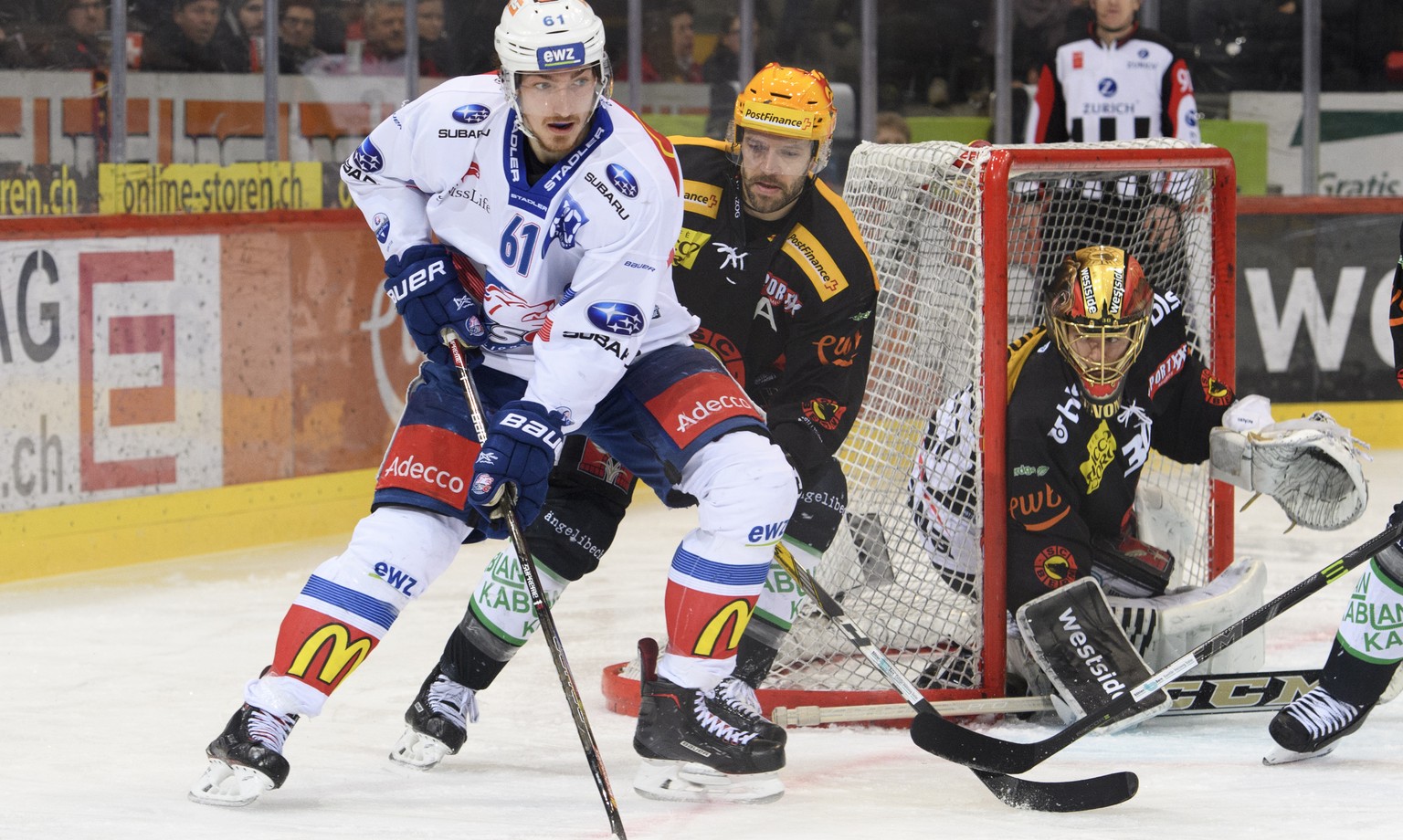 Zuercher Fabrice Herzog, links, und Berns Top Scorer Andrew Ebbett, mitte, kaempfen um den Puck, an der Seite von Bern Goalie Leonardo Genoni, rechts, im ersten Eishockey Playoff-Halbfinalspiel der Na ...