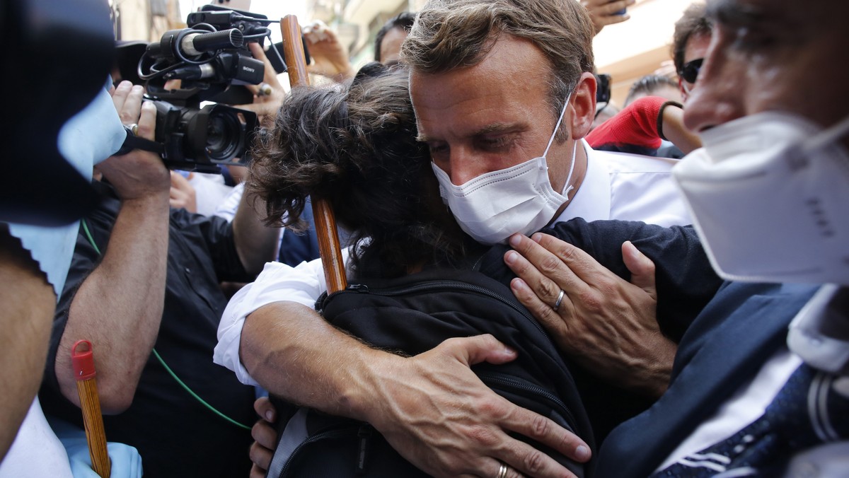 epa08587331 French President Emmanuel Macron hugs a resident as he visits a devastated street of Beirut, Lebanon, 06 August 2020. Macron arrived to Lebanon to show support after a massive explosion on ...