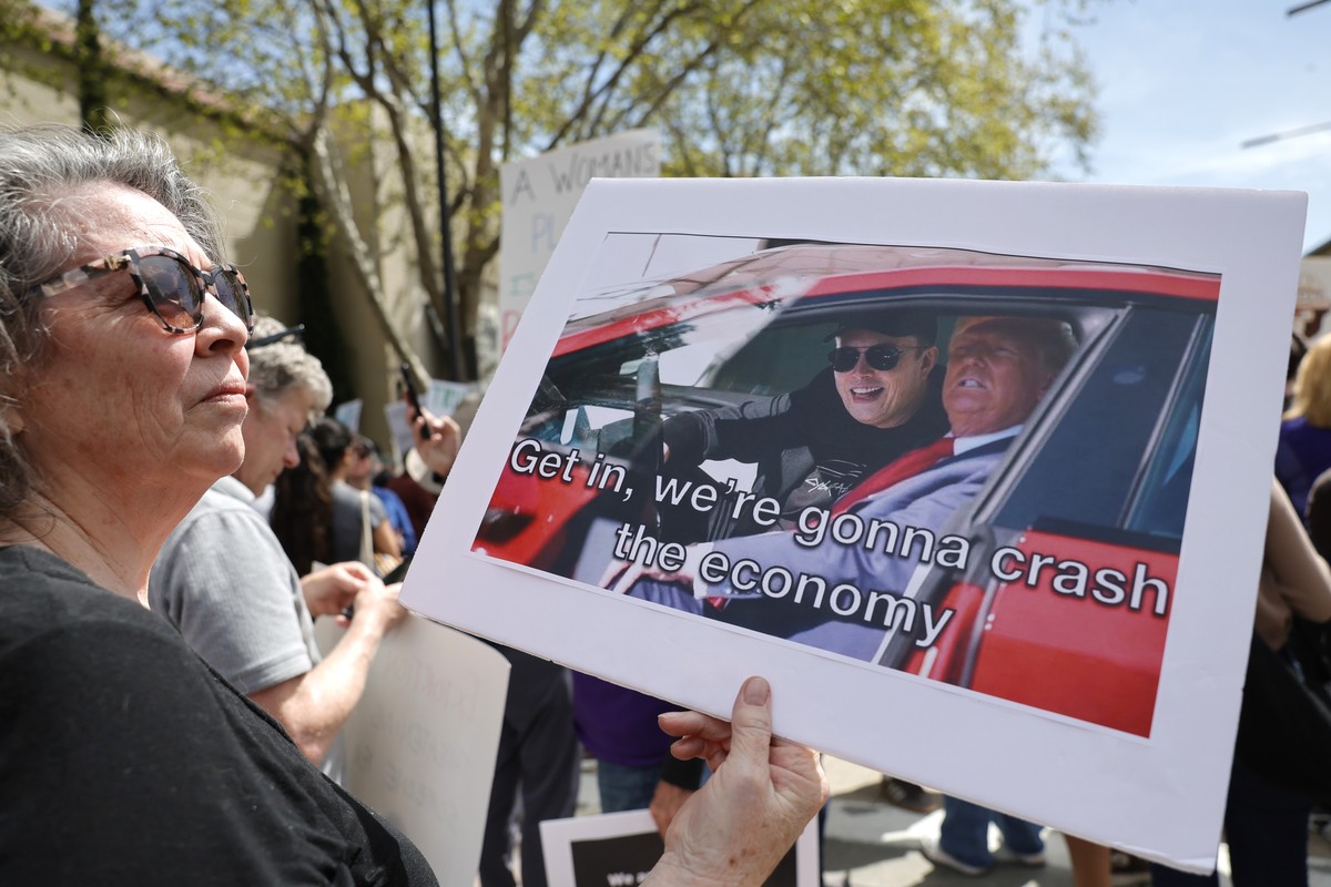 epa12012666 A protester takes part in a rally during a nationwide ?Hands Off!? protest against President Trump, his advisor Elon Musk and his policies in front of a Tesla showroom at the Broadway Plaz ...