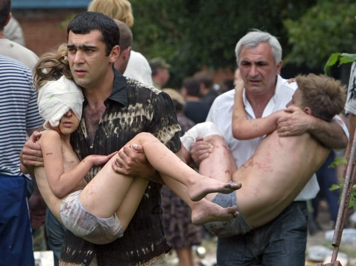 Two men carry wounded children from the school in Beslan, North Ossetia, as Russian special forces enter the building on Friday, 03 September 2004. Streams of hostages fled the besieged school in Besl ...