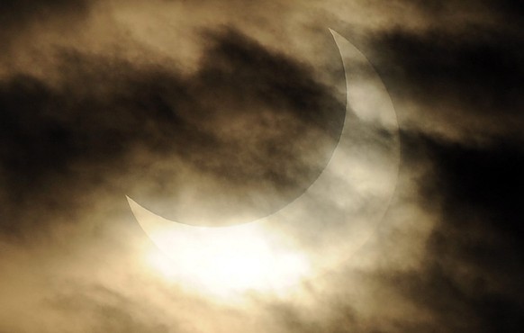 epa02515904 The sun turns sickle-shape as it is partially covered by the moon in the first solar eclipse of the New Year, over Milan, northern Italy 4 January 2011. The partial eclipse was visible alm ...