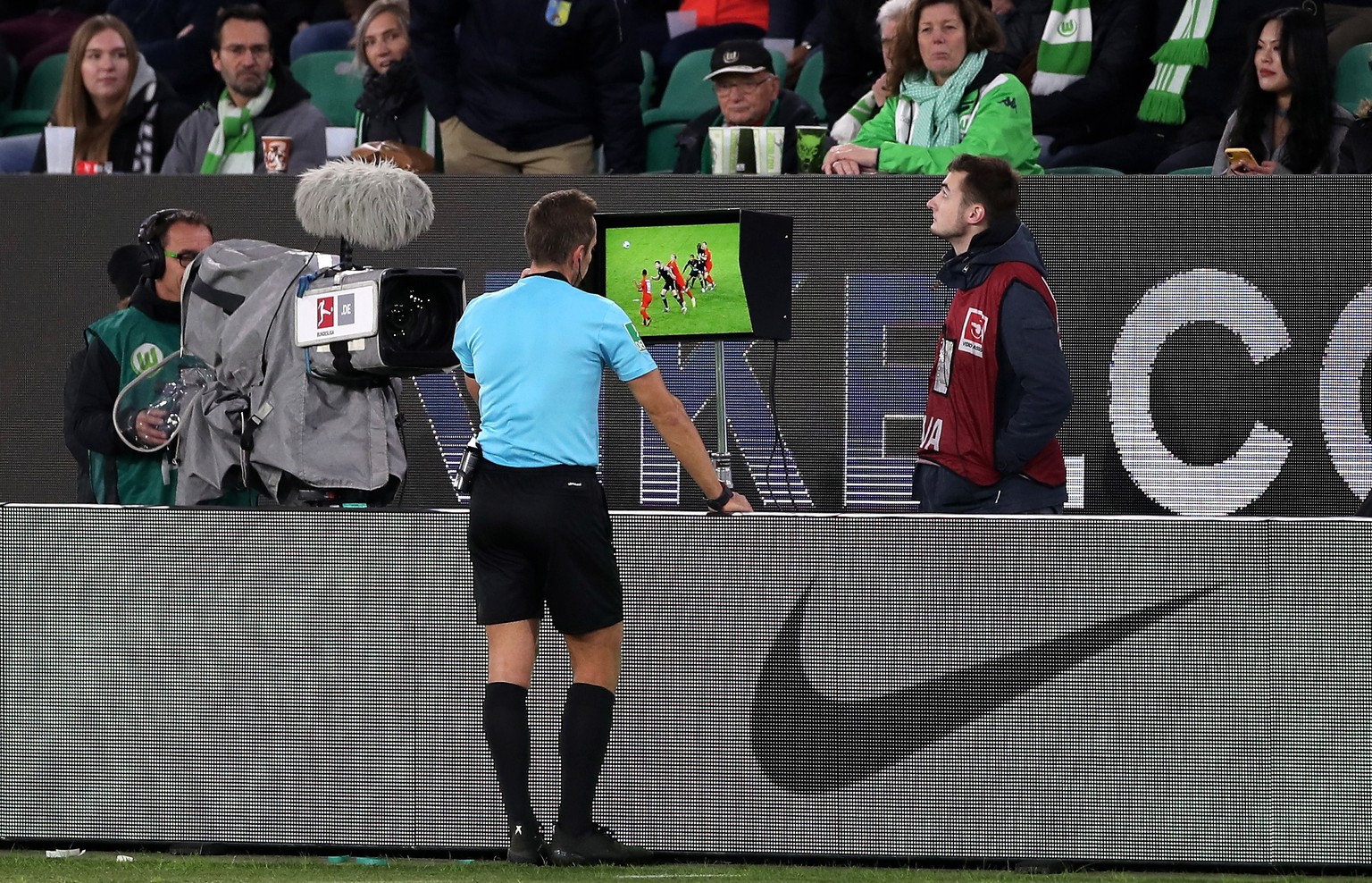 epa07954112 Referee Tobias Stieler (C) checks the VAR video review during the German Bundesliga soccer match between VfL Wolfsburg and FC Augsburg in Wolfsburg, Germany, 27 October 2019. EPA/FRIEDEMAN ...