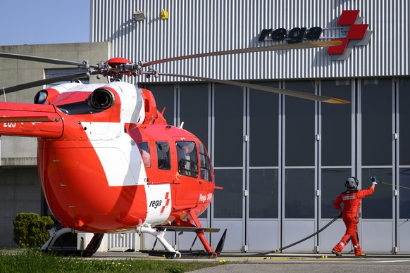 Une personne effectue le plein de carburant d&#039;un helicoptere Airbus Helicopters H145, HB-ZQJ, de la Garde aerienne suisse, Rega, apres son atterisage avant la conference de presse bilan 2021 ce j ...