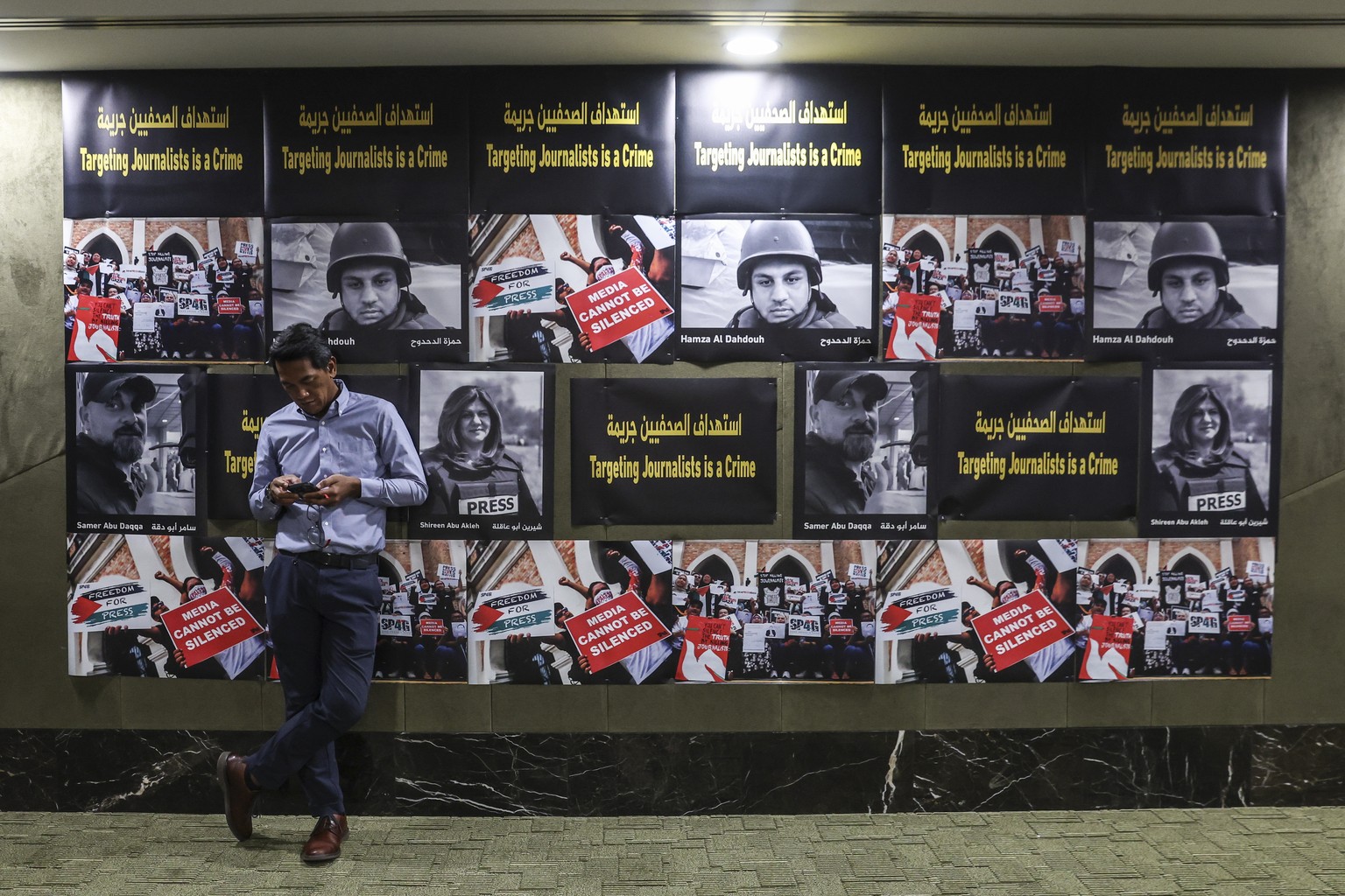 epa11316038 A man rests on posters of Al Jazeera reporter Shireen Abu Akleh, Hamza Al Dahdouh and Samer Abu Daqqa who were killed while reporting in Palestine, in conjunction with World Press Freedom  ...