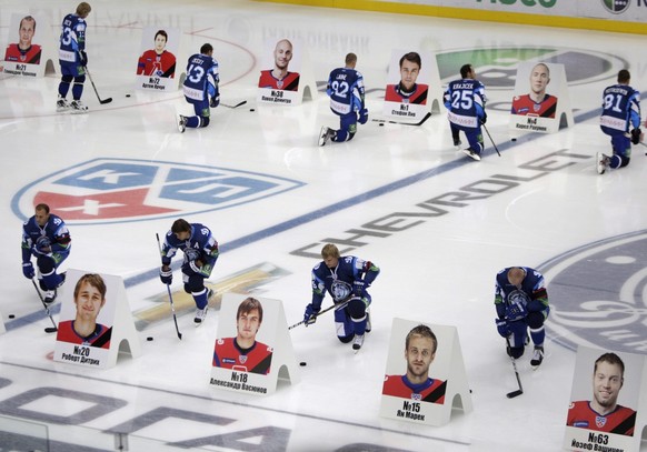 epa02904649 Players of hockey team Dinamo Minsk pay tribute in front of the portraits of Lokomotiv Yaroslavl hockey players in the Minsk-Arena stadium during a mourning ceremony in Minsk, Belarus, 08 ...