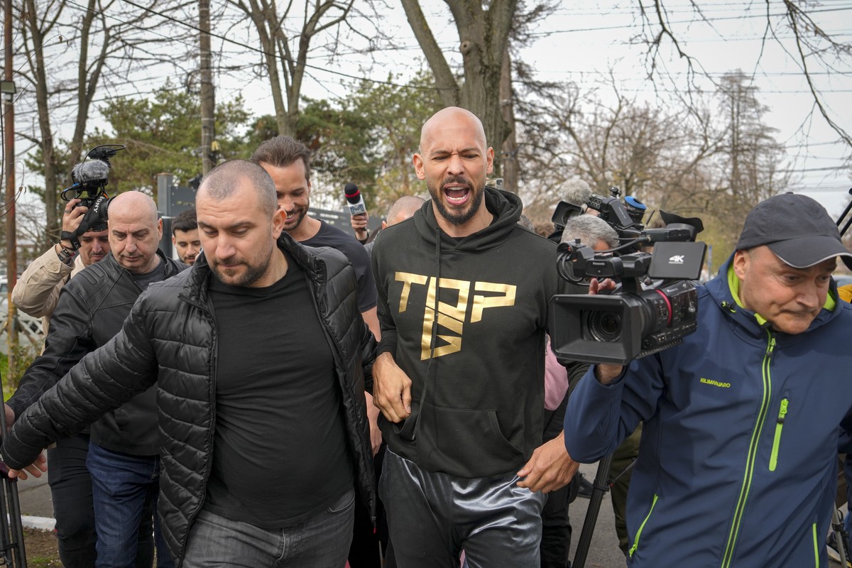 Andrew Tate reacts while speaking to media after checking in at a police station as part of his judicial control, which requires him to appear before judicial authorities in Romania when summoned, aft ...