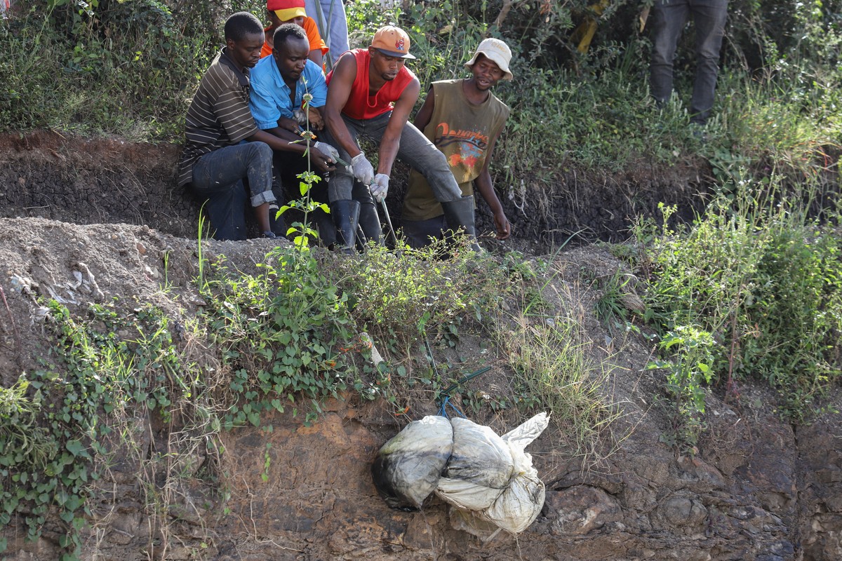 epaselect epa11474624 A group of men retrieves a body wrapped in a bag from inside a quarry turned into a dump site at Embakasi area in Nairobi, Kenya, 12 July 2024. Police stated that six severely mu ...