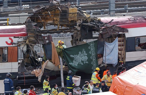 epa00151573 Rescue workers, police and medical services work alongside a bomb damaged passenger train at the Atocha station in Madrid, Spain, Thursday 11 March 2004, following a number of explosions t ...