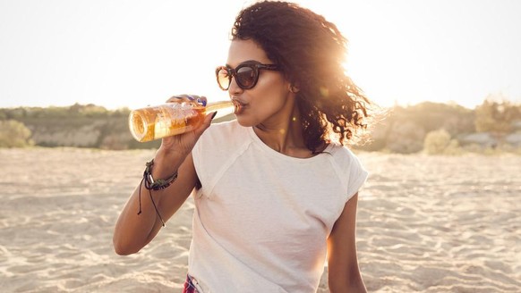 Frau trinkt Bier am Strand