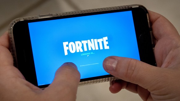 epa08621882 A person plays Fortnite on an iPhone in Miami, Florida, USA, 24 August 2020. US tech giant Apple and game developer Epic Games are in a dispute over the distribution of income from in-app  ...