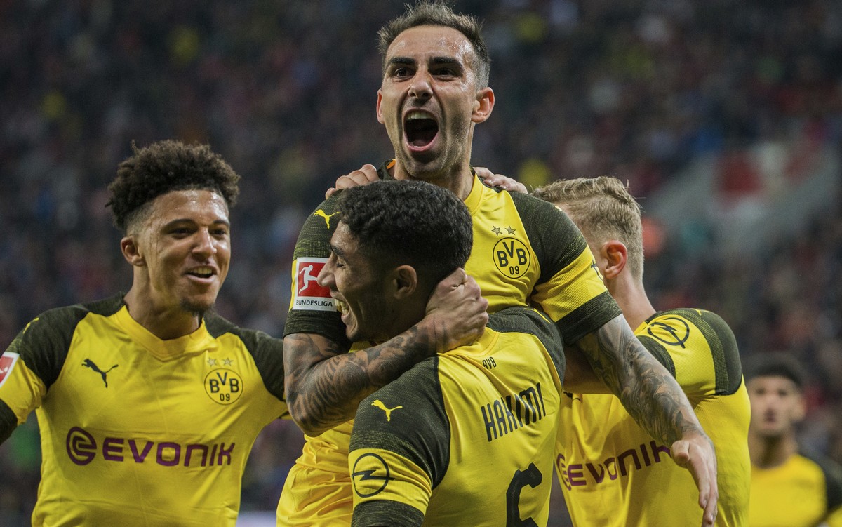 In this Sept. 29, 2018 photo Dortmund's Paco Alcacer, top, celebrates with Achraf Hakim, front, and Jadon Sancho after scoring his side's third goal in the German Bundesliga soccer match bet ...