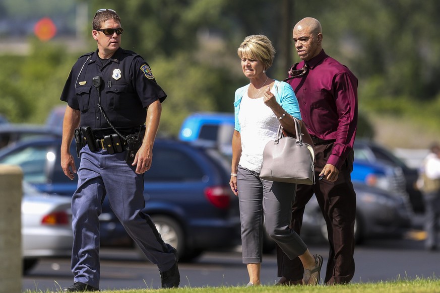 Ein Polizist eskortiert zwei Mitarbeiter des Gerichtsgebäudes in Michigan, in dem am Montag zwei Polizisten getötet wurden.