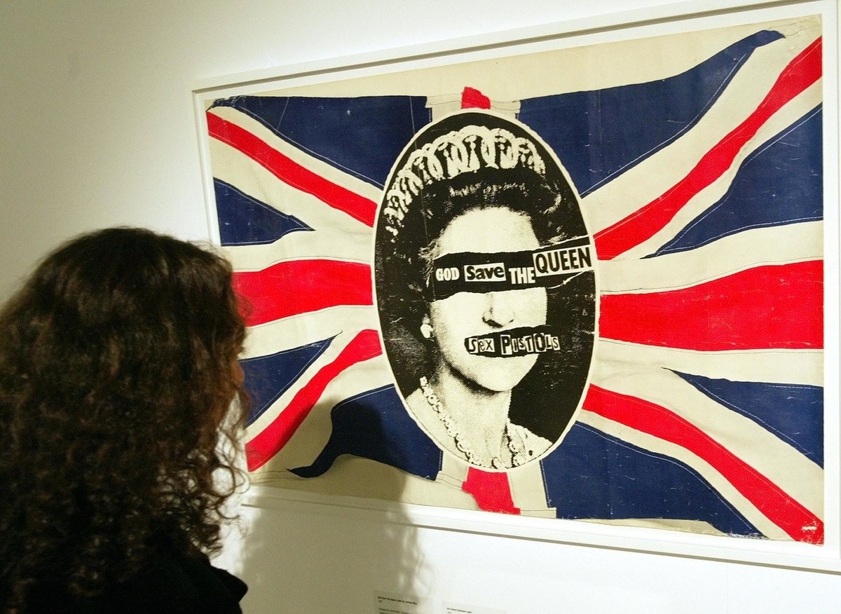 A visitor to the "Punk: A True and Dirty Tale" exhibition in central London looks at one of the most famous images from punk band the Sex Pistols, Wednesday Oct. 6, 2004. The God Save The Qu ...