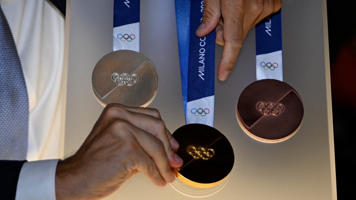 An attendee adjusts one of the Milan-Cortina 2026 Winter Olympic and Paralympic Games medals during the unveiling ceremony at Palazzo Balbi in Venice on July 15, 2025. (Photo by ANDREA PATTARO / AFP)