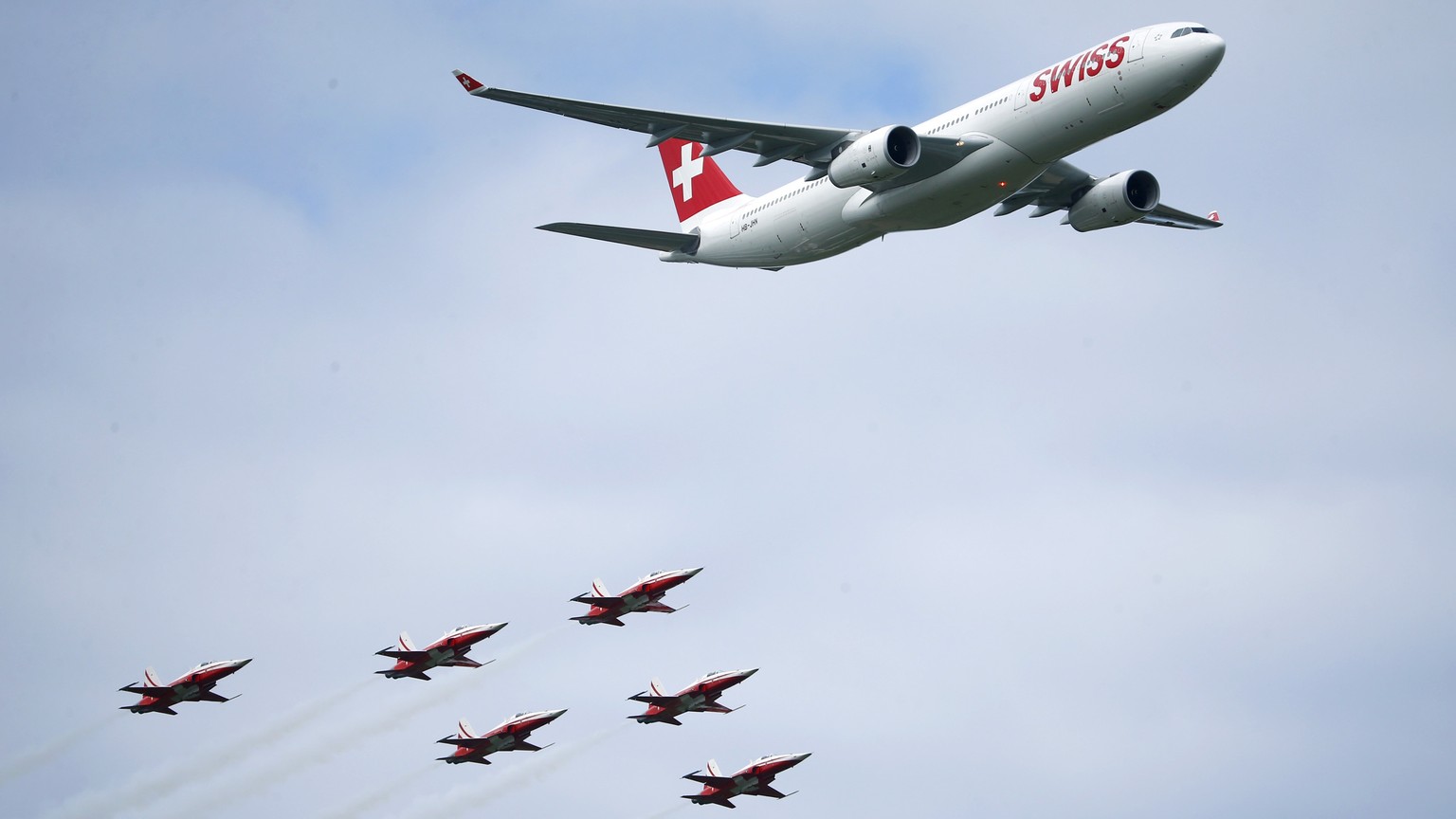 An Airbus A330 aircraft of Swiss International Air Lines and Switzerland&#039;s Air Force national flight team Patrouille Suisse in their Northrop F-5E Tiger II aircrafts perform during the Air14 airs ...