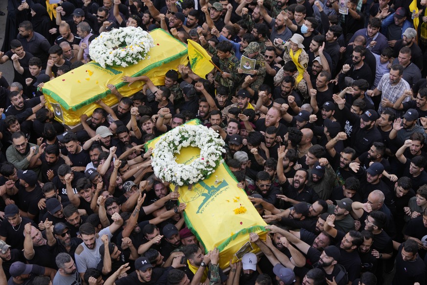 Hezbollah members carry the coffins of two of their comrades who were killed on Wednesday when a handheld device exploded, during a funeral procession in the southern suburbs of Beirut, Thursday, Sept ...