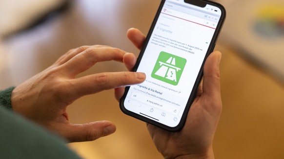 Eine Frau loest eine elektronische Vignette, die E-Vignette, zur Nutzung von abgabepflichtigen Autobahnen und Autostrassen fuer das Jahr 2024 auf ihrem Telefon, aufgenommen am Freitag, 1. Dezember 202 ...