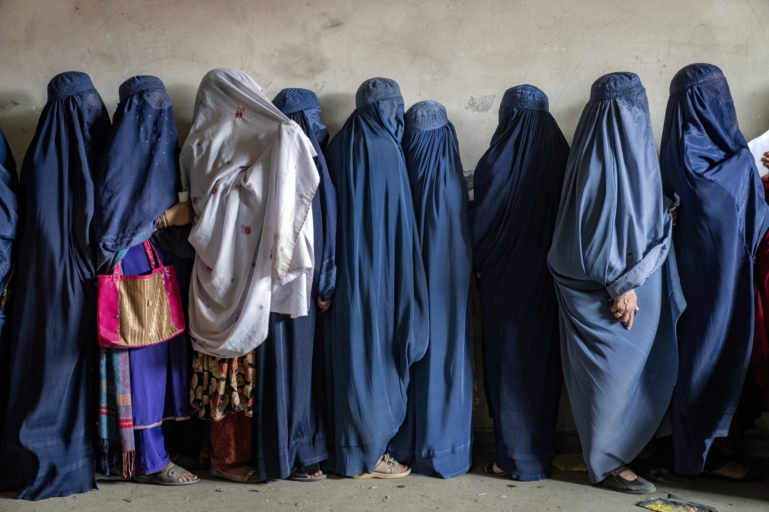 FILE - Afghan women wait to receive food rations distributed by a humanitarian aid group, in Kabul, Afghanistan, on May 23, 2023. Afghan women feel scared or unsafe leaving their home alone because of ...