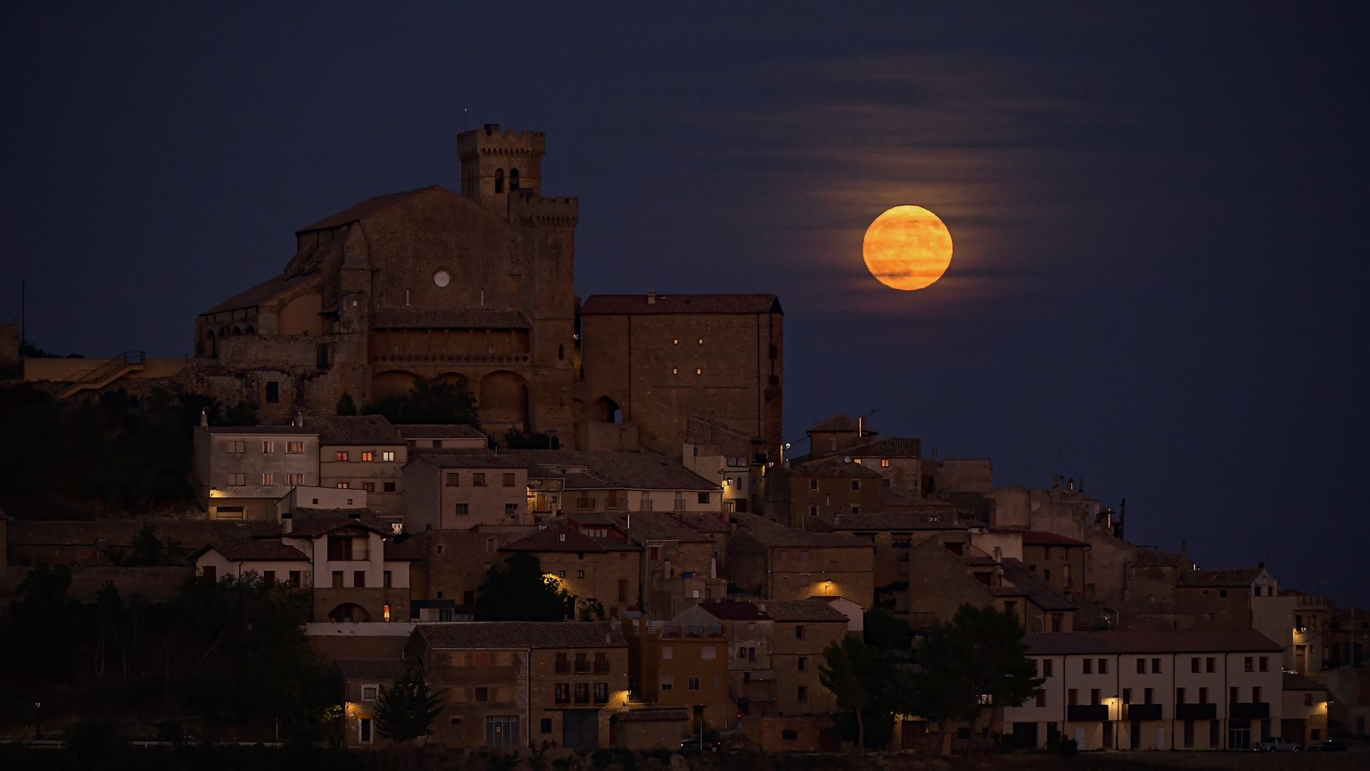 The moon known as blue moon rises behind the small village of Ujue, northern Spain, Wednesday, Aug. 30, 2023. (AP Photo/Alvaro Barrientos)