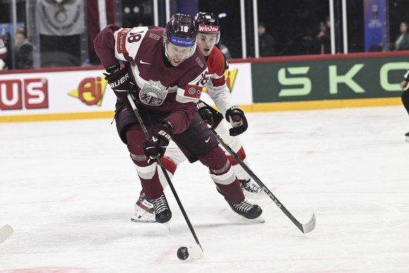 Latvia's Rodrigo Abols, left, and Austria's Marco Kasper, right, challenge for the puck during the IIHF Ice Hockey World Championship group A match between Latvia and Austria in Stockholm, S ...