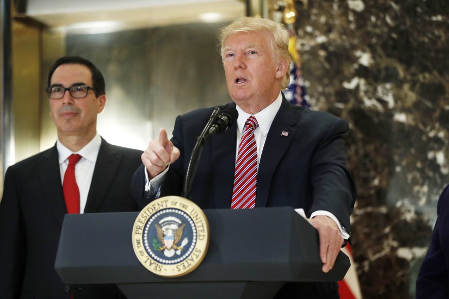 President Donald Trump, accompanied by Treasury Secretary Steven Mnuchin, speaks to the media in the lobby of Trump Tower in New York, Tuesday, Aug. 15, 2017. (AP Photo/Pablo Martinez Monsivais)