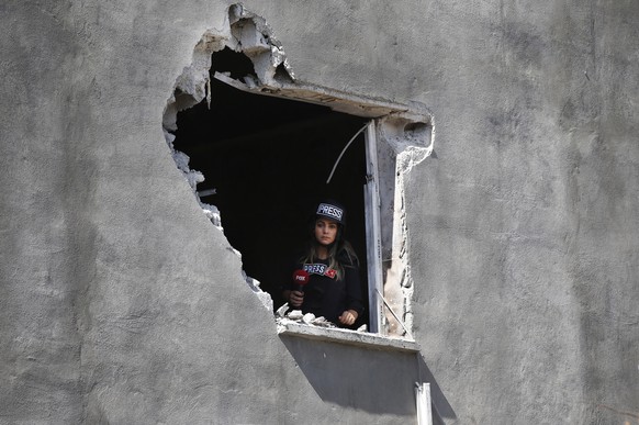 A journalist looks out of an hole on a house that was damaged by a mortar fired from inside Syria, on the Turkish town of Akcakale, southeaster, Turkey, Saturday, Oct. 12, 2019.Nobody got hurt by the  ...