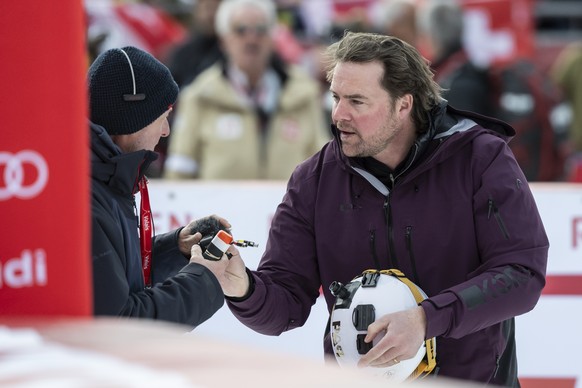 Former Swiss ski racer Marc Berthod hands over his data to a cameraman after racing down the course with a video camera $ in action / reacts in the finish area during the men's Downhill race at t ...