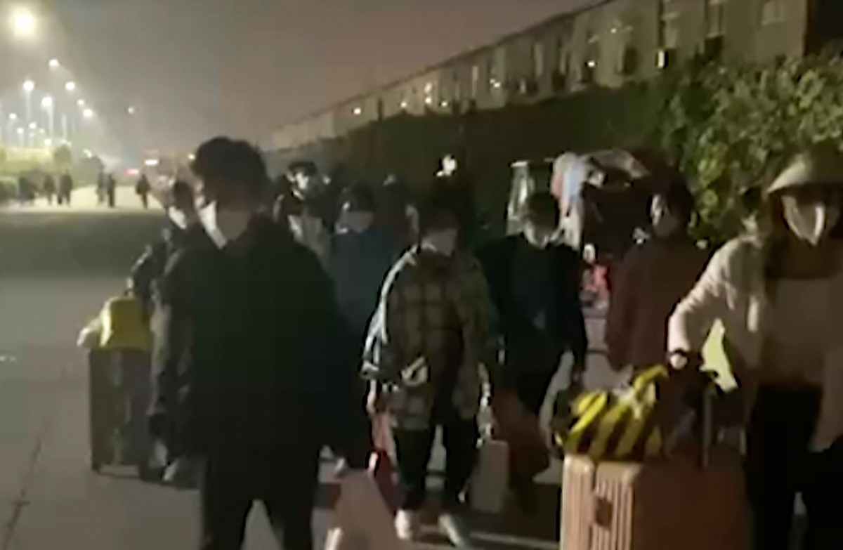 In this photo taken from video footage and released by Hangpai Xingyang, people with suitcases and bags are seen leaving from a Foxconn compound in Zhengzhou in central China's Henan Province on  ...