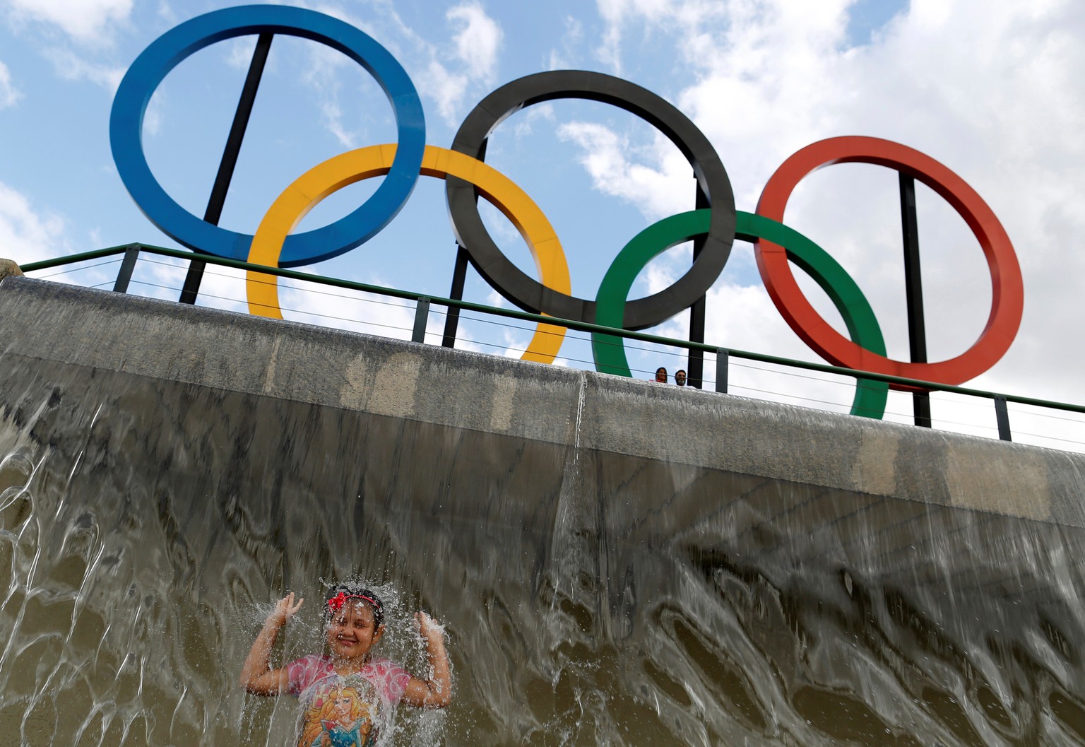 A child plays in water near Olympic rings placed at Madureira Park ahead of the Rio 2016 Olympic Games in Rio de Janeiro, Brazil, July 17, 2016. REUTERS/Bruno Kelly