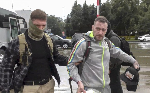epa11517306 A handout still image taken from handout video provided by the Russian Federal Security service (FSB) shows Russian FSB Oficer escorts German Patrick Schoebel (R) to a plane during a priso ...